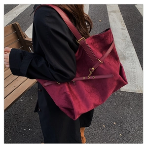 Close-up of burgundy suede tote bag featuring vintage bronze buckle and strap details