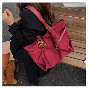 Detail of burgundy faux suede tote bag featuring retro beaded charm and adjustable strap