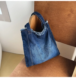 Detail of blue denim tote bag with palm tree print and rustic frayed edge fringe design