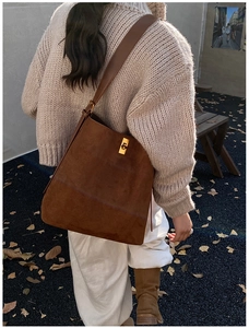 Chic dark brown suede tote bag styled with a beige sweater and autumn leaf backdrop
