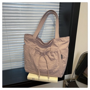 Detail of dry rose pink nylon tote bag featuring front drawstring and fashion label