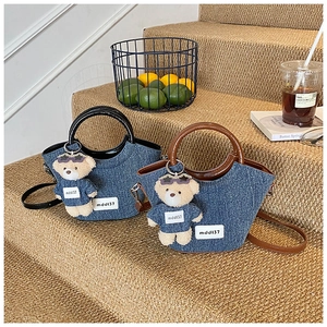Detail showing denim bucket bags with PU handles and a cute plush bear charm accessory