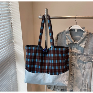Détail du sac cabas à carreaux montrant le tissu patchwork et les anses résistantes