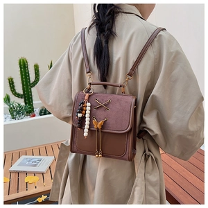 Detail of vintage brown backpack featuring leather stitching and a gold bow metal clasp