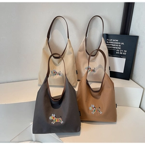 Detail of embroidered zebra canvas tote bags in four colors on minimalist display