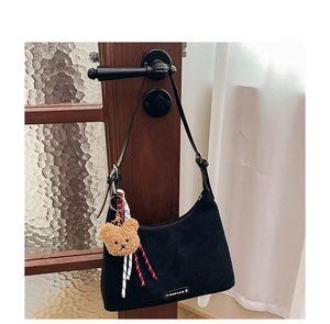 Détail du sac hobo noir mat avec logo métallique et breloque ours en peluche