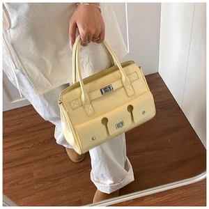 Détail d'un sac à main en cuir jaune crème montrant le fermoir argenté et la poche