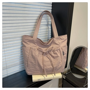 Detail of a dusty pink tote bag showing the drawstring bow pocket and FASHION side label