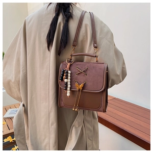 Detail of vintage brown bow backpack featuring suede texture and wooden bead tassel
