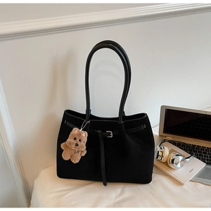 Black suede tote bag with slim shoulder straps and a brown plush bear charm
