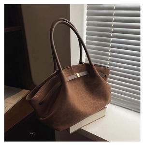 Détail d'un sac cabas marron vintage à motif léopard avec boucle dorée et texture mate