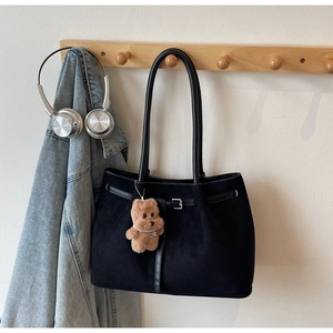 Detail of black suede tote bag featuring a decorative strap and brown plush bear charm