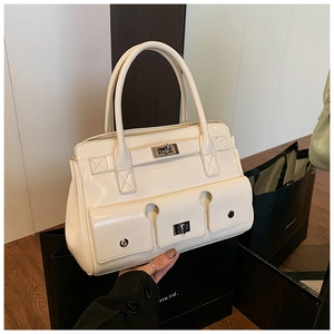 Détail du sac à main blanc cassé avec trois poches extérieures et fermoirs pivotants dorés