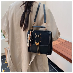 Detail shot of a black bow-accented backpack with gold hardware and beaded charm