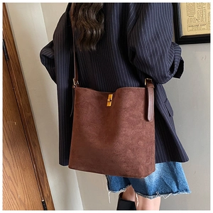 Close-up of golden swivel lock and brown matte suede texture on large tote bag