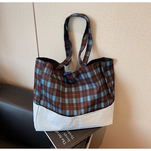 Gros plan d'un grand sac cabas à carreaux avec tissu écossais et boucle bleue décorative