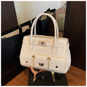 Détail d'un sac à main crème verni avec fermoirs rotatifs argentés et doubles poches avant