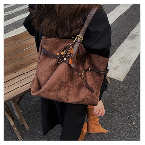 Brown suede tote bag with leather straps and wood bead detail in urban street setting