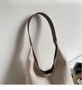 Detail view of durable brown leather handles and beige canvas material on tote bag