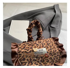 Close-up of leopard print handbag with satin ruffles and small bear decorative charm
