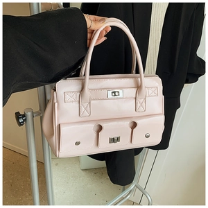 Détail d'un sac à main rose clair avec fermoir rotatif argenté et doubles poches