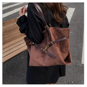 Detail view of coffee suede tote bag with dark brown leather straps and gold buckle