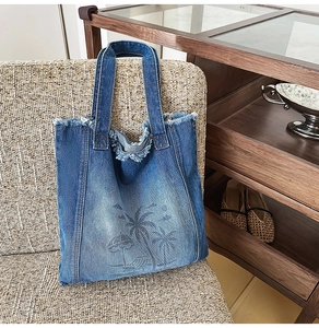 Detail of blue denim tote bag with tropical beach print and frayed fringe edge