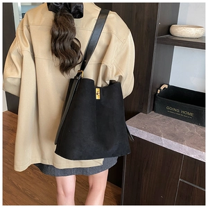 Detail of black matte suede bucket bag featuring a refined gold metal twist lock closure