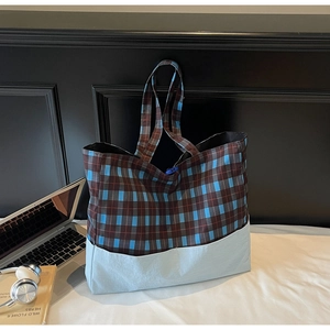 Détail du grand sac cabas à carreaux avec ordinateur et livres dans une chambre douillette