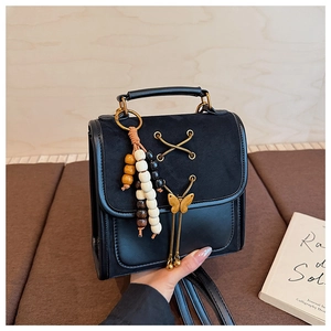 Detail of black mini backpack with metallic butterfly and colorful bead charm