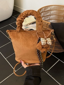 Brown suede bucket tote bag with ruched handle and plush bear charm accessory