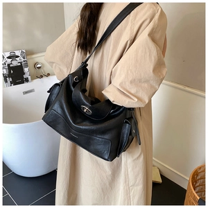 Detail of black pebbled leather tote bag with metal turn-lock and side pockets