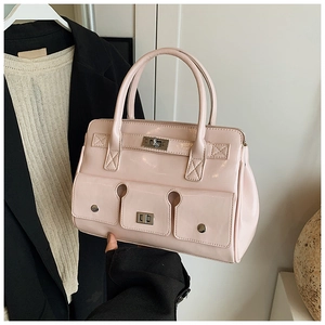 Gros plan du sac à main rose en cuir verni avec fermoir tournant en métal et doubles anses