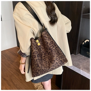 Detail of leopard print tote bag featuring a gold square twist lock and black shoulder strap