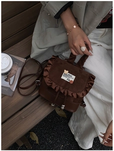 Detail of a brown leopard print backpack with ruffle flap and drawstring on a wooden bench