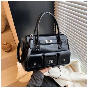 Détail d'un sac à main noir brillant avec fermoirs rotatifs argentés et poches avant