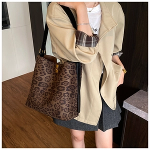 Detail of leopard print tote bag featuring gold twist lock and adjustable strap