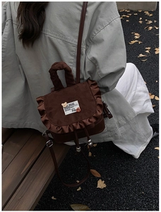 Detail of vintage brown mini backpack with ruffle trim and cute bear emblem on wooden bench