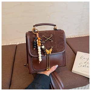 Detail of dark brown vintage backpack with suede stitching and wood bead butterfly charm