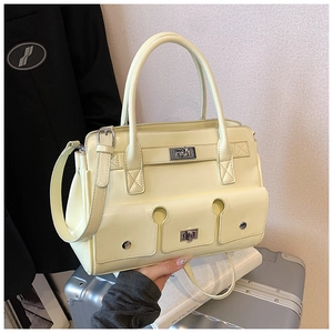 Détail du sac à main beige en similicuir avec double fermoir rotatif sur valise