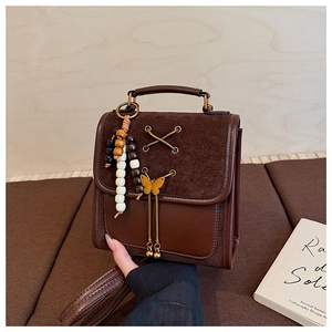 Detail of vintage brown leather handbag featuring suede flap and metal bow accents