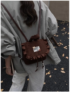 Detail of dark brown suede backpack with ruffle trim and cute bear logo label
