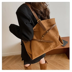 Detail of adjustable dark brown strap and gold buckle on a retro suede tote bag