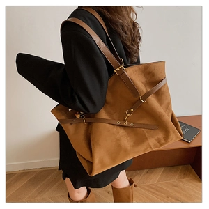 Side view of large brown suede tote bag with leather straps on model in black suit