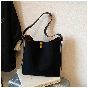 Detail of minimalist black matte tote bag featuring a golden metal turn-lock and leather strap