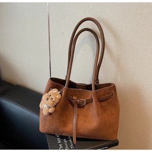Close-up of vintage brown suede tote bag with belt buckle detail and bear charm decoration
