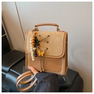 Detail of vintage beige backpack with bow charm and elegant criss-cross strap design
