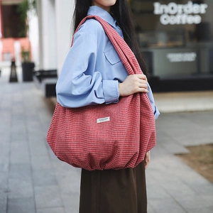 Dettaglio della borsa tote in nylon a quadri rossi con ampia tracolla alla moda