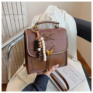 Detail of vintage brown leather backpack with metal bow buckle and wooden bead tassel