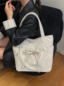 Large beige canvas tote bag with drawstring bow detail and multi-pocket design